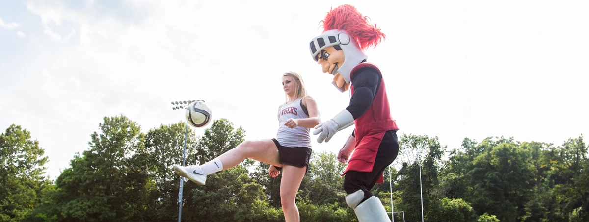 Student playing soccer with Scarlet Knight